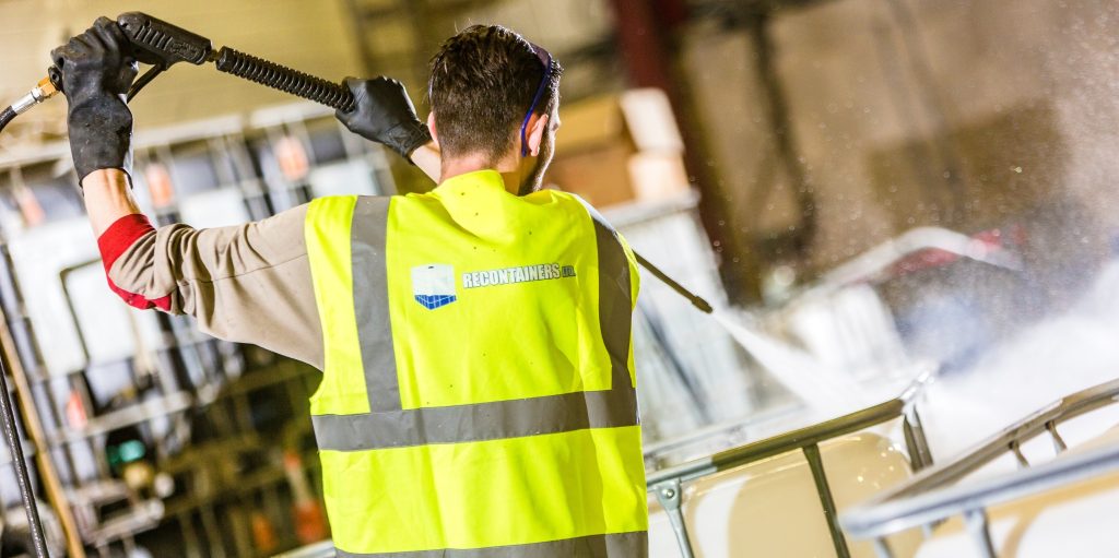 Technician cleaning and inspecting IBC fittings to ensure leak-free connections.